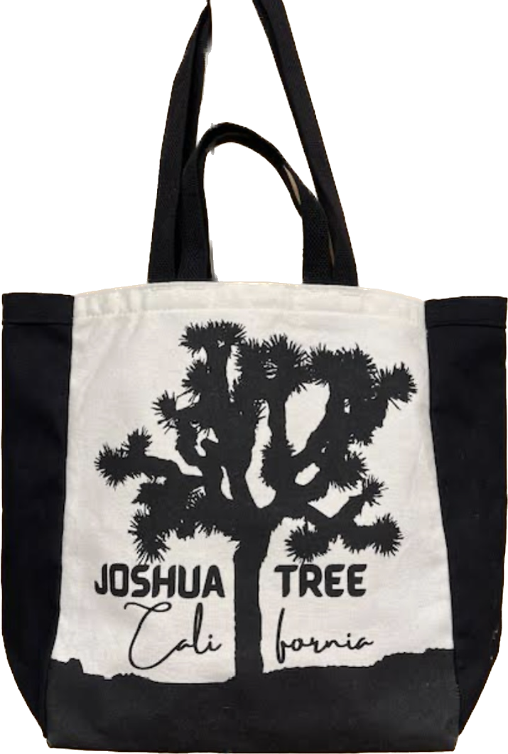 The image shows an ivory picnic bag with black handles. On the front of the bag is a black silhouette of a Joshua tree, with the words "JOSHUA TREE" and "CALIFORNIA" written below it.